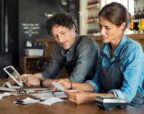 Hospitality business owners reviewing receipts and costs to manage cash flow, pricing and business performance