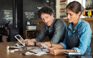 Hospitality business owners reviewing receipts and costs to manage cash flow, pricing and business performance
