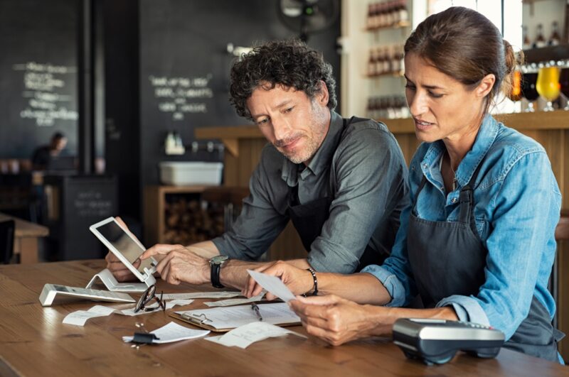 Hospitality business owners reviewing receipts and costs to manage cash flow, pricing and business performance