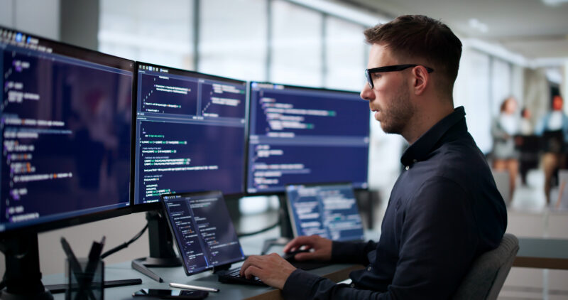 Technology professional working across multiple screens, reflecting investment in AI, digital tools and productivity improvements highlighted in the Thrive Index.